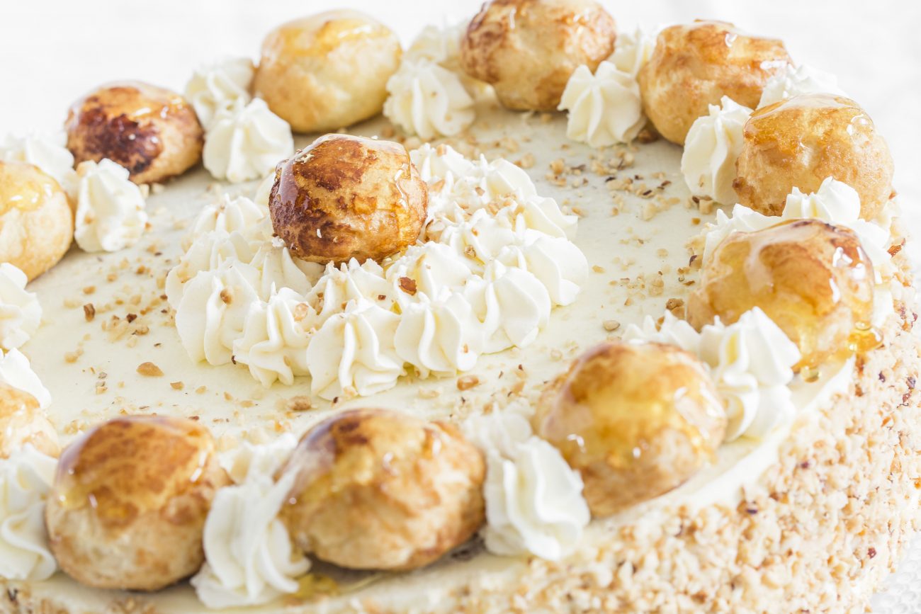 Close up image of the top of a Saint Honore cake with lots of cream and caramel decorations.