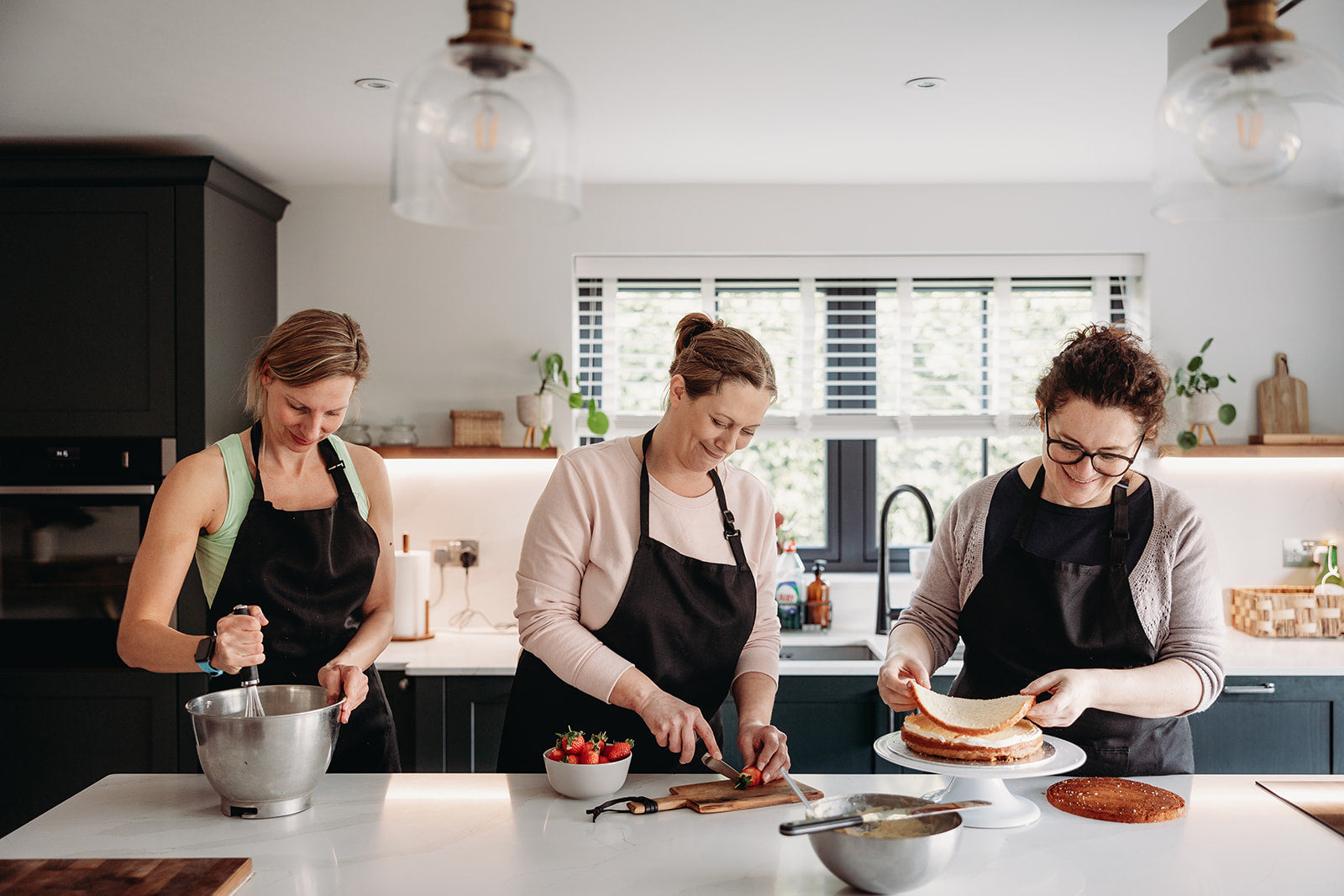 Three women in a kitchen baking Italian food.