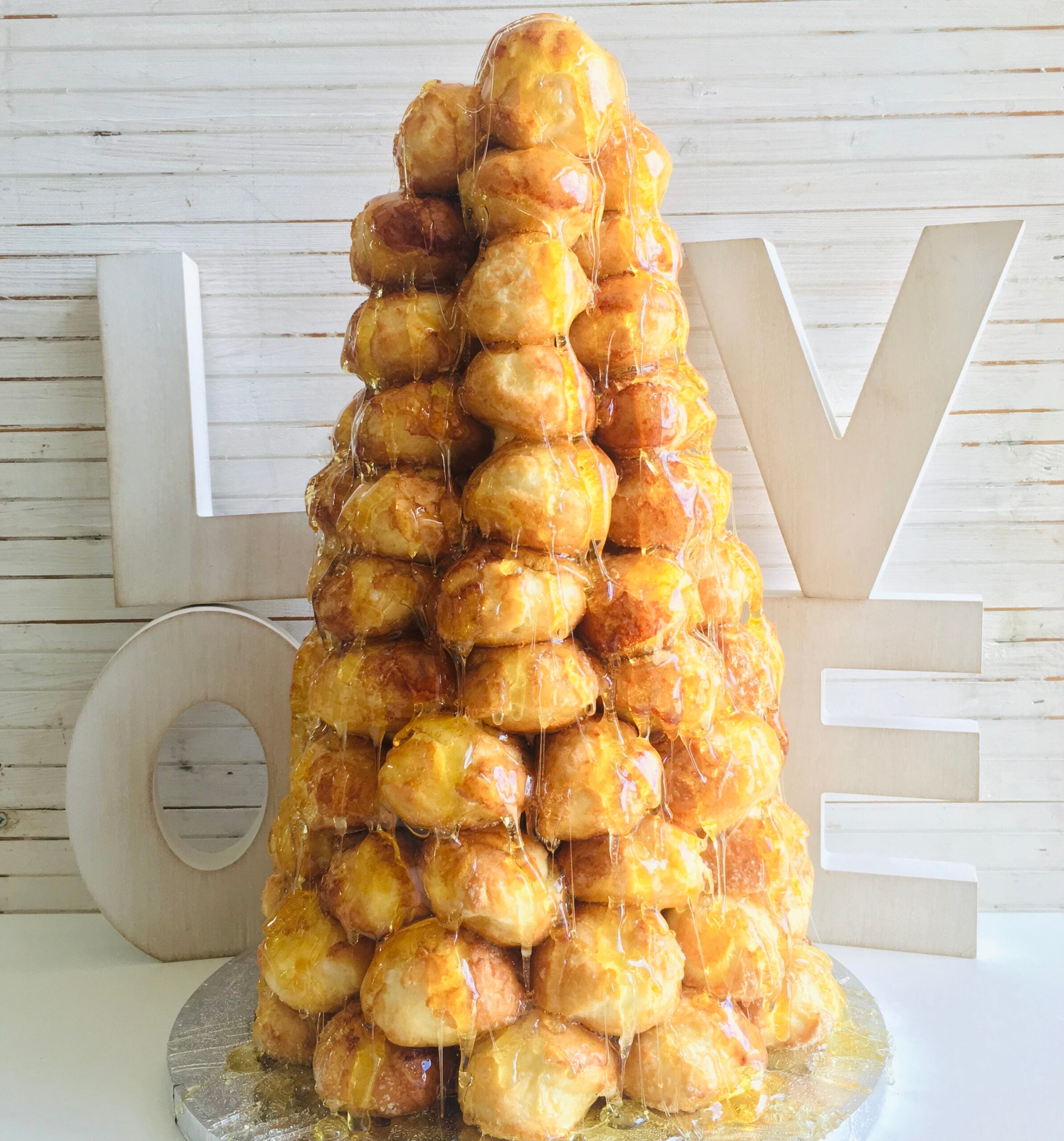 Close up of a small, tiered croquembouche made of profiteroles, filled with cream, and coated in caramel,