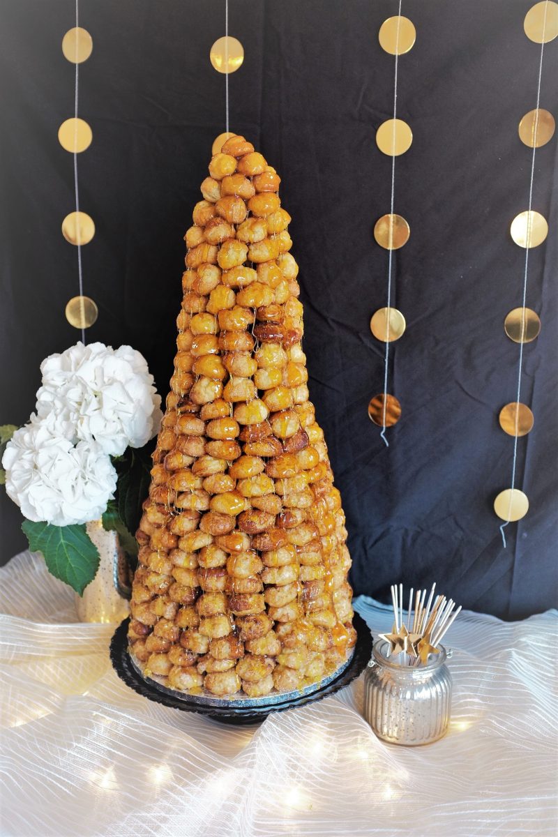 A tall, tiered croquembouche made of profiteroles, filled with cream, and coated in caramel designed for a corporate event.