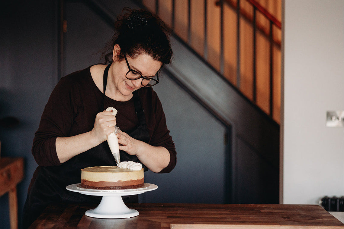 Person decorating a cake in a home setting