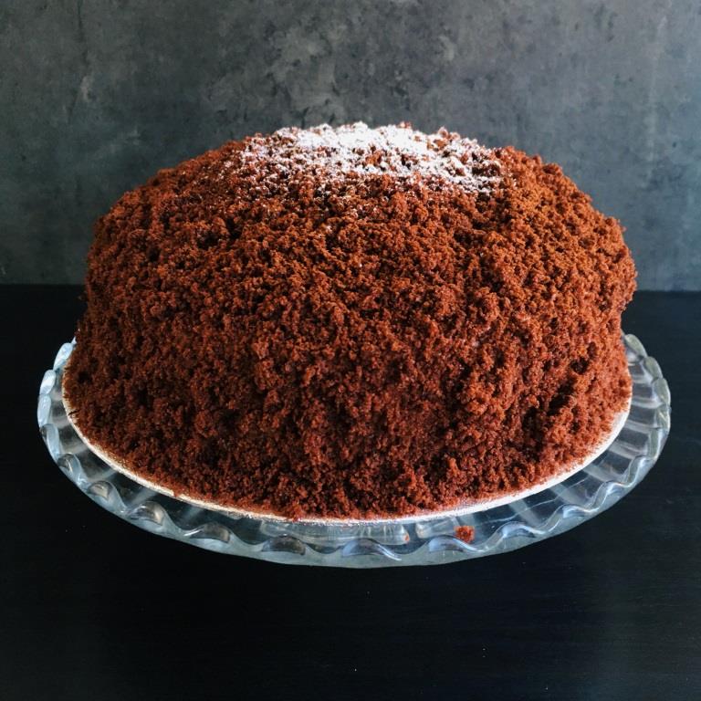 A Chocolate Mimosa cake, served on a plate with a fork, against a grey background. Made by Cambridge based bakery Biscotti di Debora.