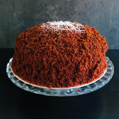 A Chocolate Mimosa cake, served on a plate with a fork, against a grey background. Made by Cambridge based bakery Biscotti di Debora.