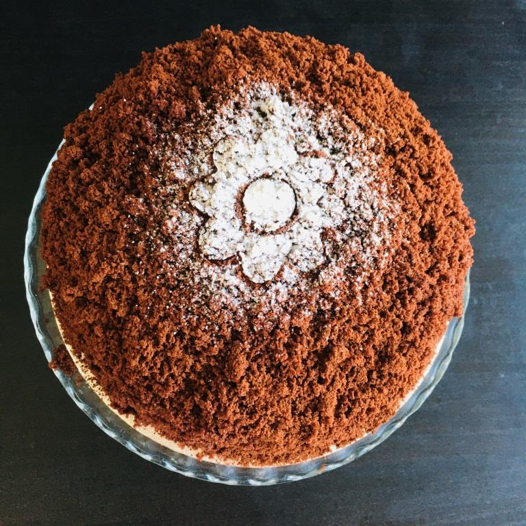 A Chocolate Mimosa cake, served on a plate with a fork, against a grey background. Made by Cambridge based bakery Biscotti di Debora.