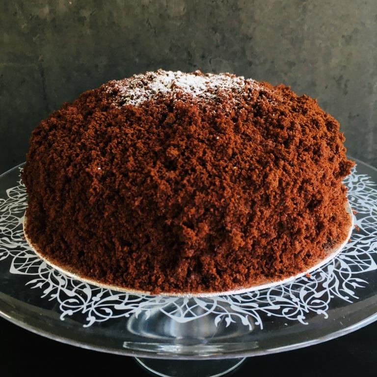 A Chocolate Mimosa cake, served on a plate with a fork, against a grey background. Made by Cambridge based bakery Biscotti di Debora.