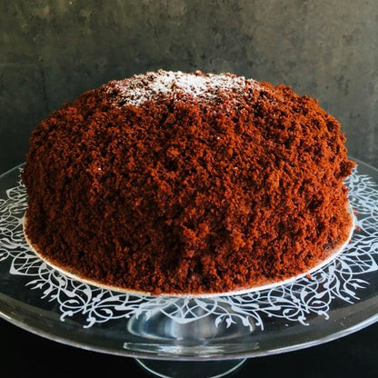 A Chocolate Mimosa cake, served on a plate with a fork, against a grey background. Made by Cambridge based bakery Biscotti di Debora.
