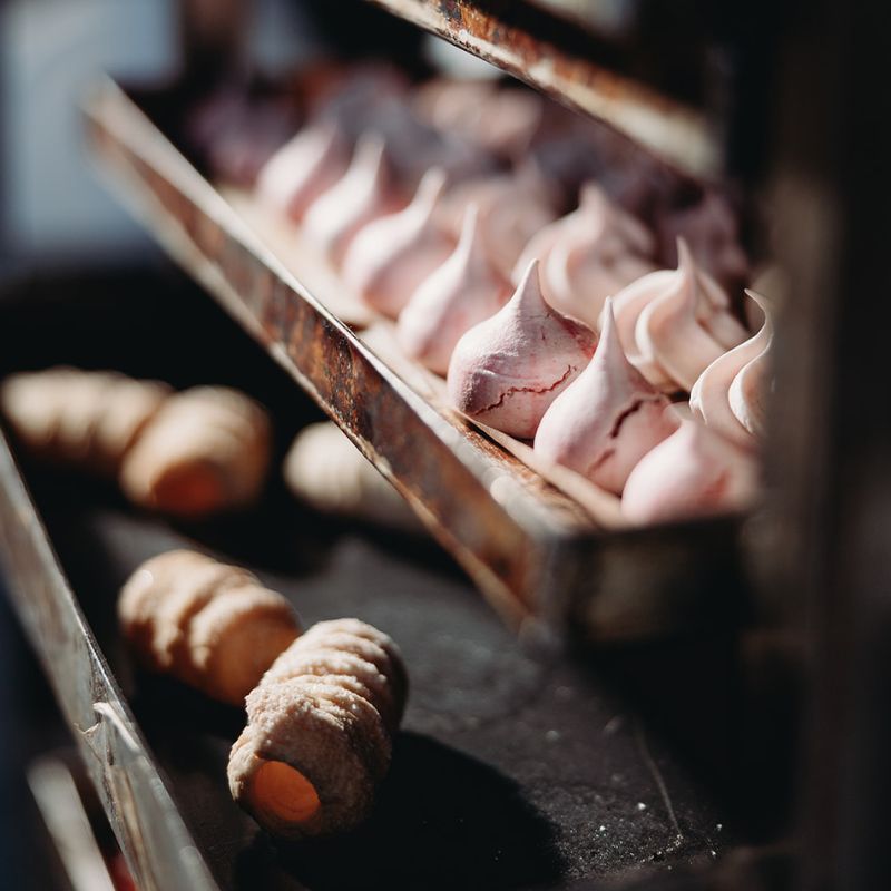 Close-up of pink meringues on a metal tray with blurred background