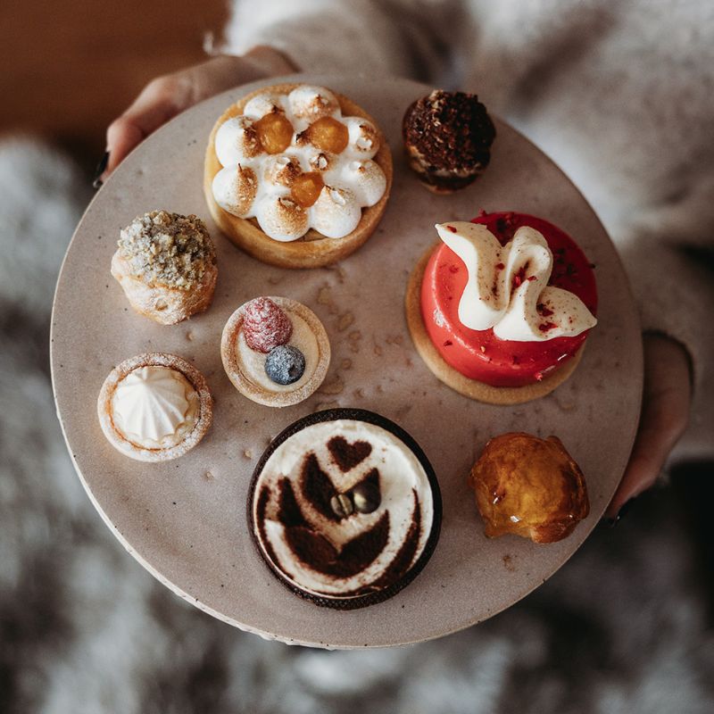 Assorted Petit fours pastries on a plate held by a person