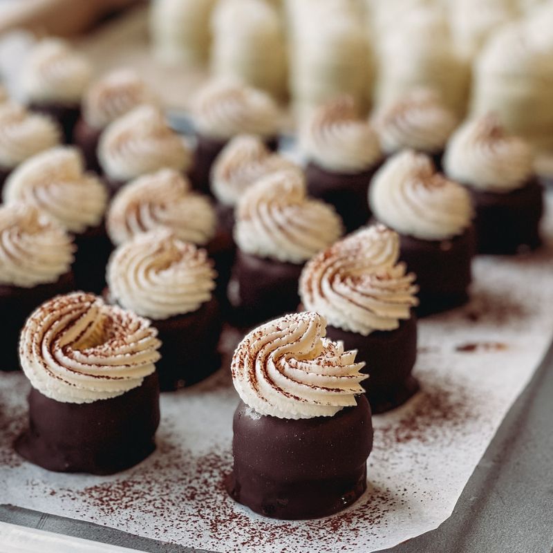 Chocolate petit fours treats with swirl toppings on a surface