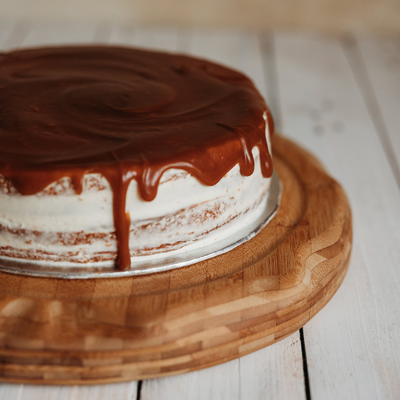 Salted caramel cake sat on a wooden chopping board