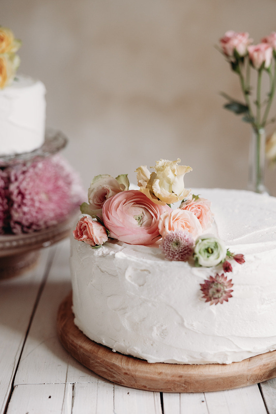 White cake with floral decorations on a wooden board, with a blurred background